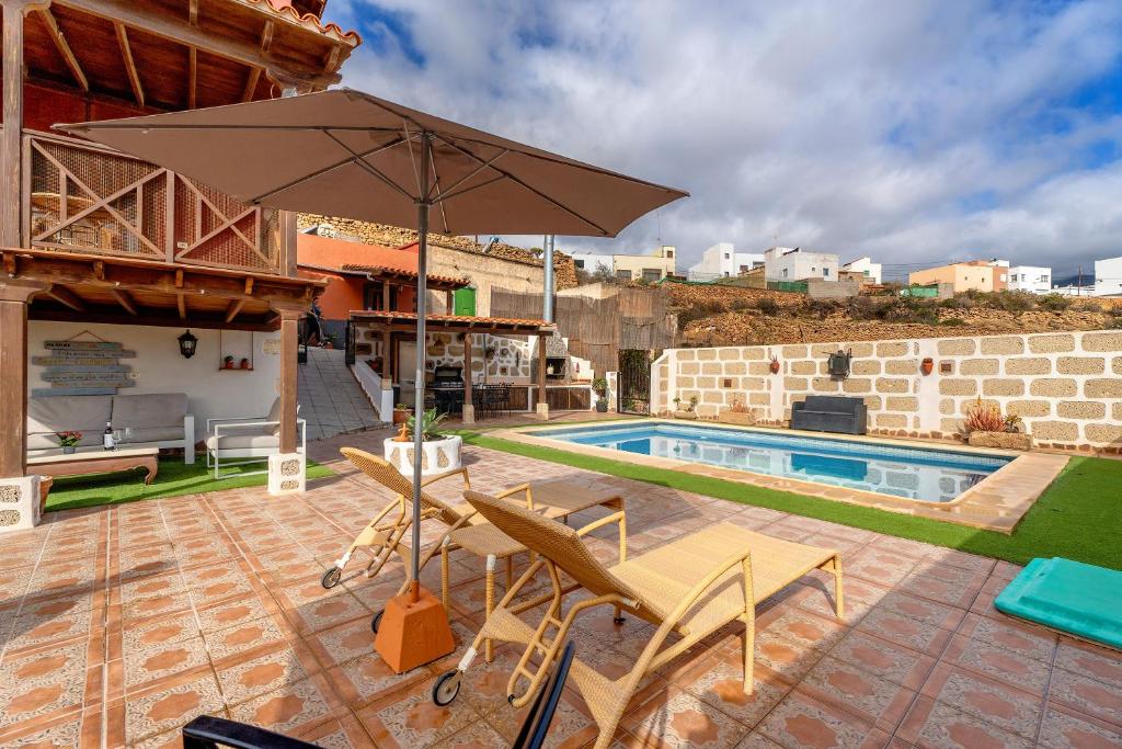 een patio met een parasol en stoelen en een zwembad bij Casa Elvira in Chimiche