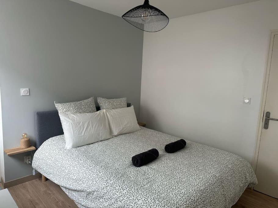 a bed with a black and white comforter and pillows at Le 41 in Dijon