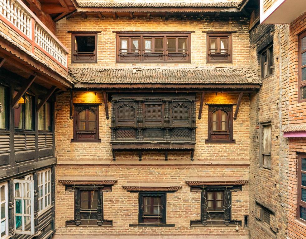 Edificio alto de ladrillo con ventanas y balcón en Manju Baha Hotel & Restaurant, en Bhaktapur