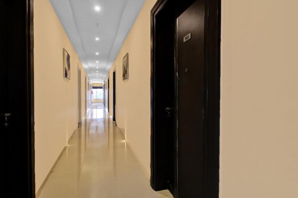 a hallway with black doors and white walls at SPOT ON Anay Inn in Nagpur