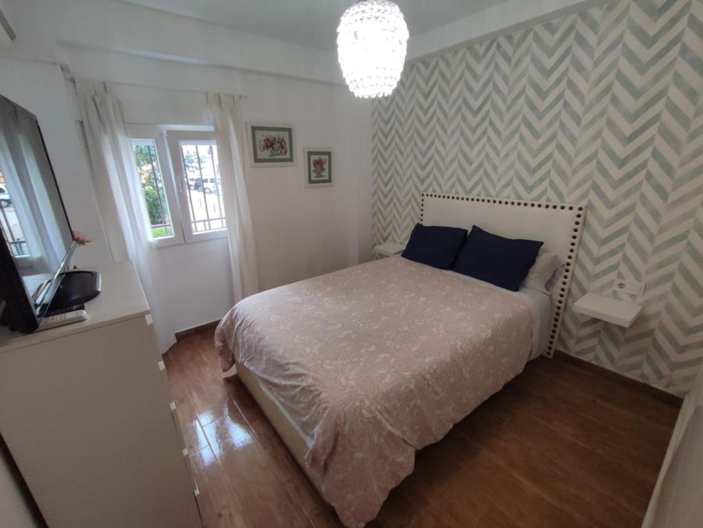 1 dormitorio con 1 cama con almohadas azules y TV en piso reformado 3 habitaciones, en Sevilla