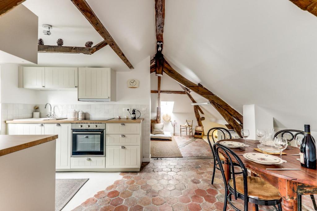 une cuisine avec des armoires blanches et une table avec des chaises dans l'établissement Appartement de charme sous les toits, à Paris