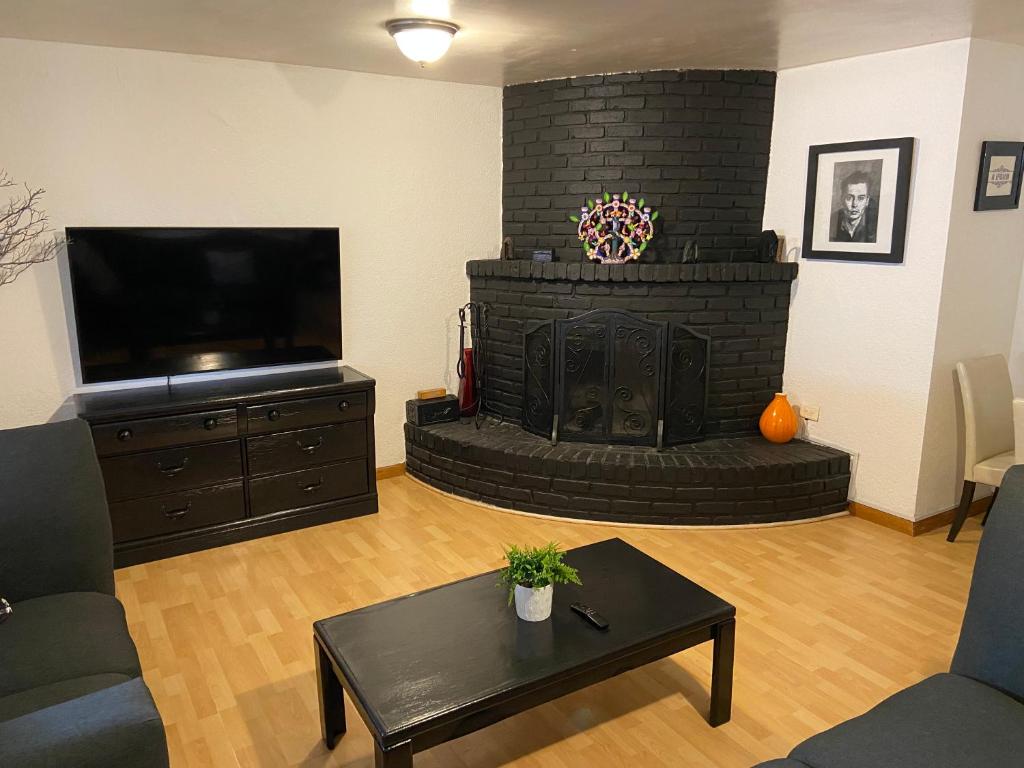 sala de estar con chimenea y TV de pantalla plana en Quetzal House, en Tijuana