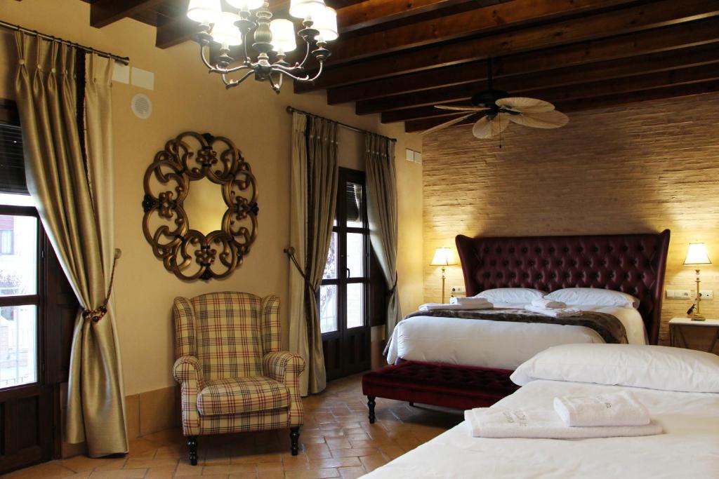 a bedroom with two beds and a chair and a mirror at Casa Rural Andalucia Mia in Aracena