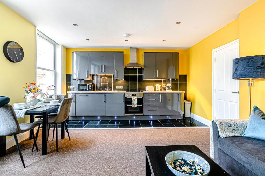 Brighton Lanes Cosy One Bedroom Apartment في برايتون أند هوف: غرفة معيشة مع مطبخ بجدران صفراء