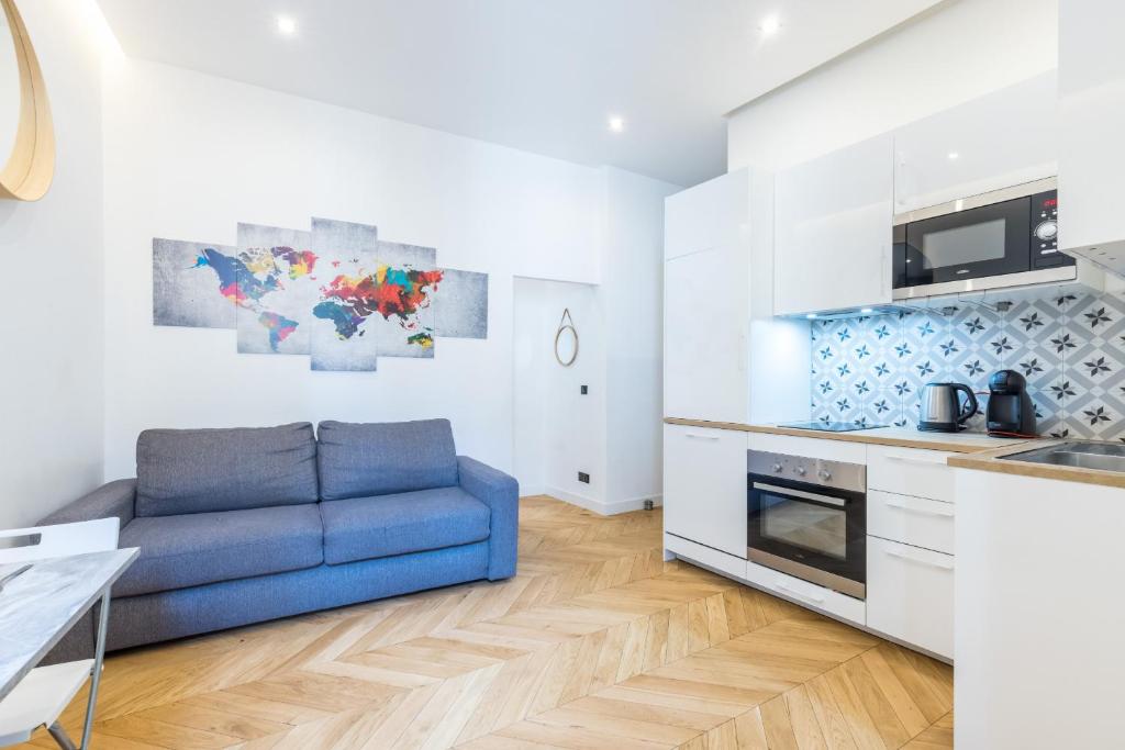 a living room with a blue couch in a kitchen at Massena Square - Ultra Central 1 Bdr in Nice