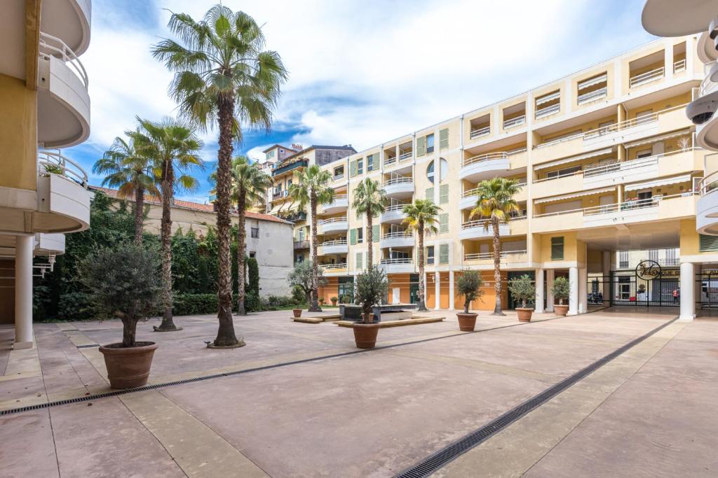 a large building with palm trees in a courtyard at Quiet 1 bdr Port! close Place du Pin Garibaldi in Nice