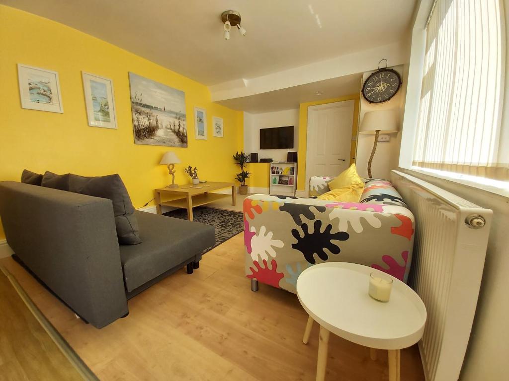 uma sala de estar com um sofá e uma mesa em Beautiful Two Bedroom ground floor apartment em Swansea