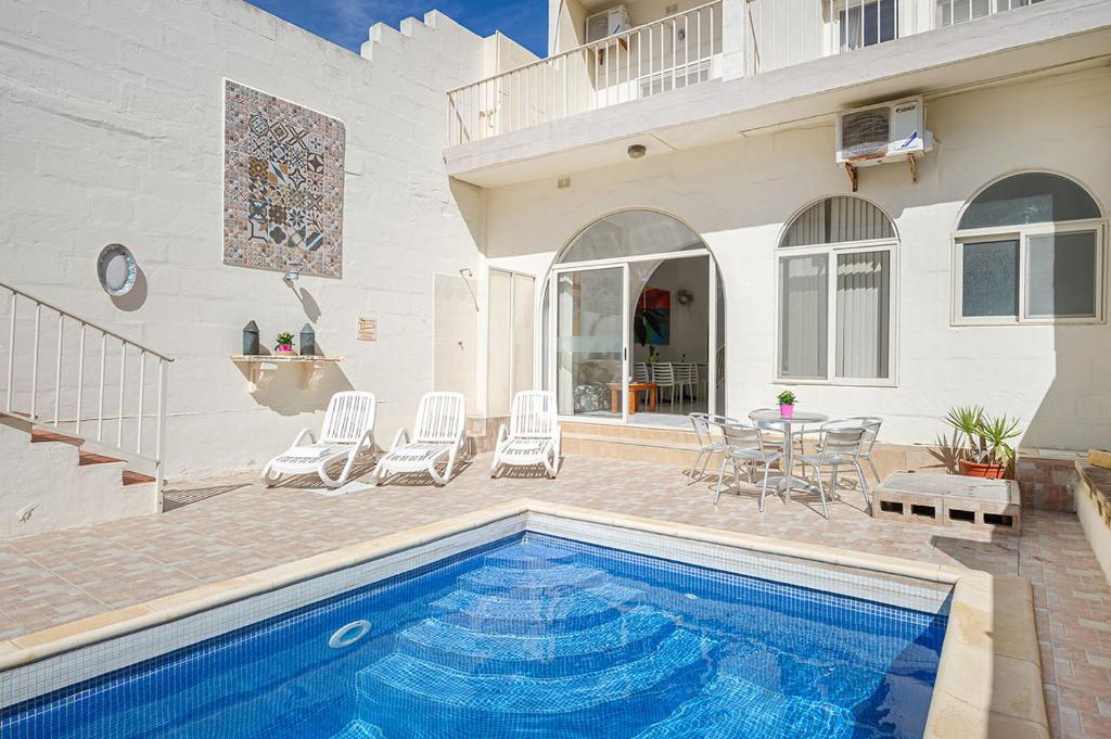 a house with a swimming pool and a table and chairs at Phase Guesthouse in Xewkija