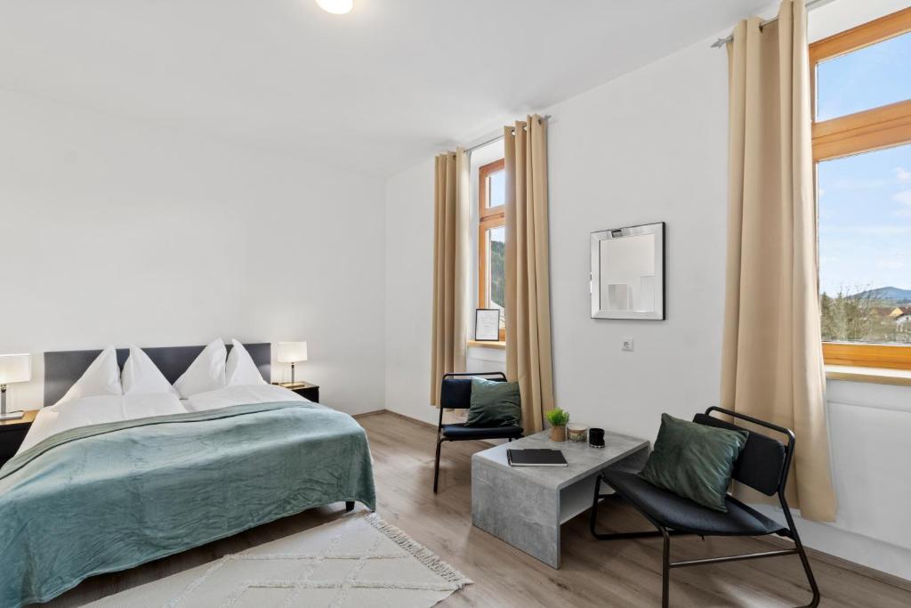 a white bedroom with a bed and a chair at FarawayHomes Studio Sankt Michael #10 in Sankt Michael in Obersteiermark