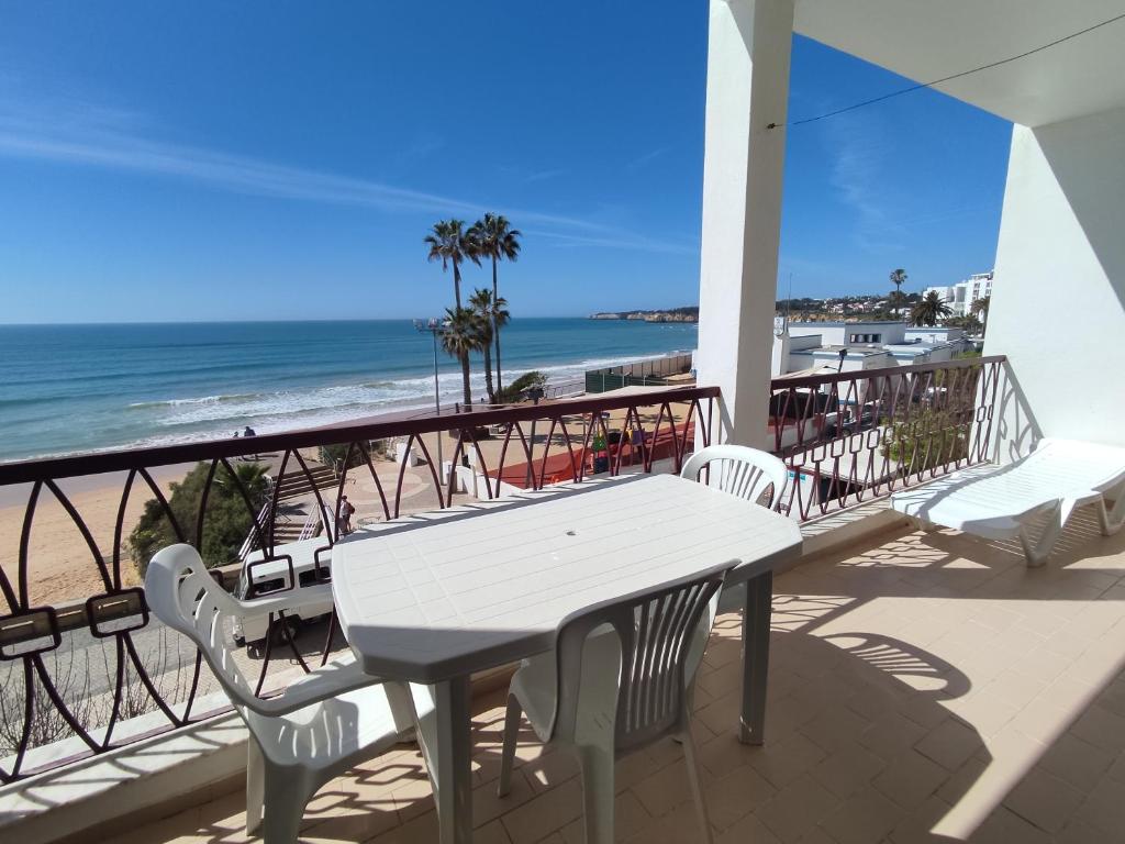 einen weißen Tisch und Stühle auf einem Balkon mit Strandblick in der Unterkunft 2 Avenida Frente Mar - Casas & Papéis in Armação de Pêra