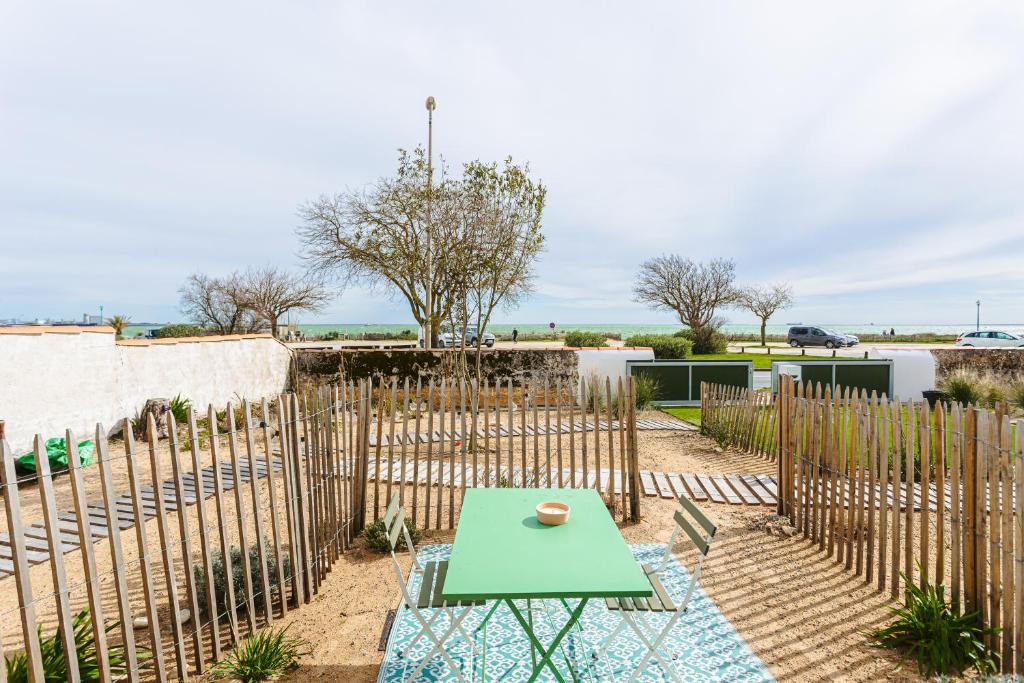 a patio with a green table and a fence at La Plage, T2 vue mer in Rivedoux-Plage