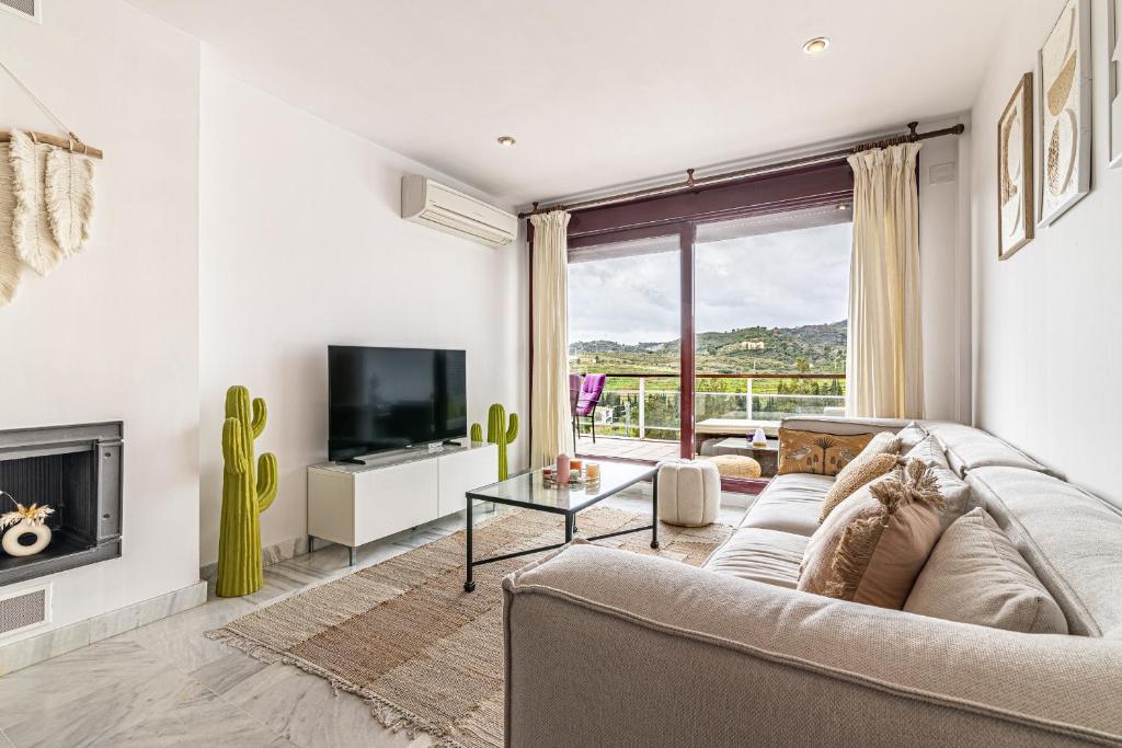 a living room with a couch and a tv at RentitSpain Charming Apartment in Parque Botanico Resort & Country Club, Marbella, Estepona, Benahavis in Estepona