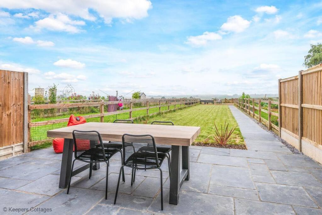 a patio with a table and chairs and a field at Meadow View in Deal