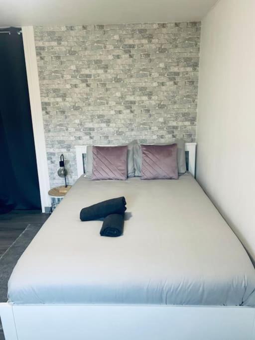 - un grand lit blanc avec une chaussure noire dans l'établissement Studio au calme, à Beauvais