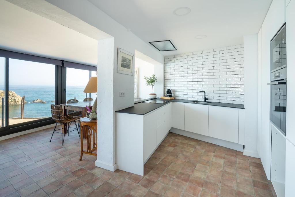 a kitchen with white cabinets and a view of the ocean at Hostal Sa Malica in Blanes