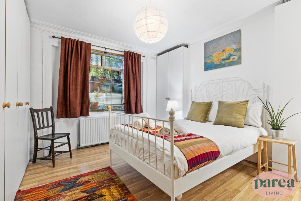 a white bedroom with a bed and a chair at Parea Living - Cosy 1-Bed Artistic Flat at Newington Green in London