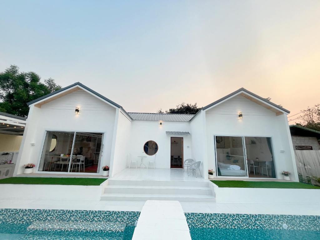 een wit huis met een zwembad ervoor bij บ้านยายเจี๊ยบ พูลวิลล่าเชียงคาน Pool Villa ChiangKhan in Amphoe Chiang Khan