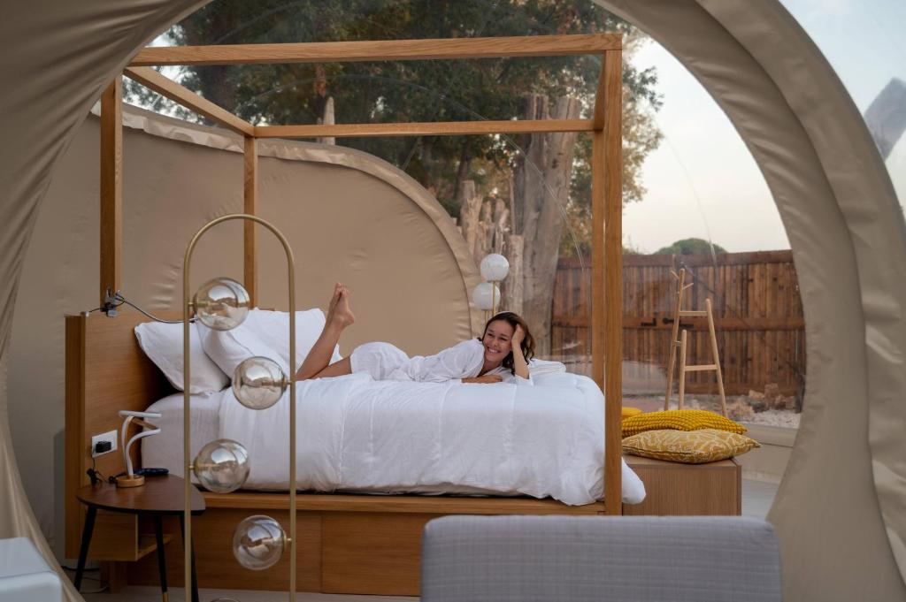 Una donna sdraiata su un letto in una tenda di Bubble Room Suite Experience - Bolla Savio Ravenna a Savio di Ravenna