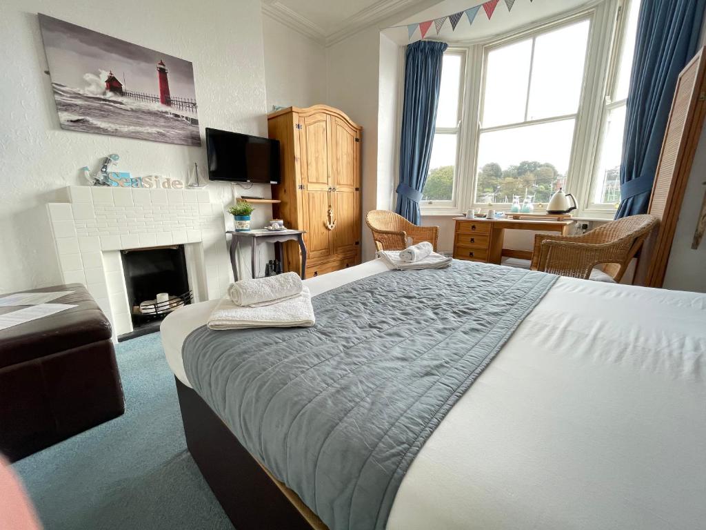 a bedroom with a large bed and a fireplace at Seascape guest house in Melcombe Regis
