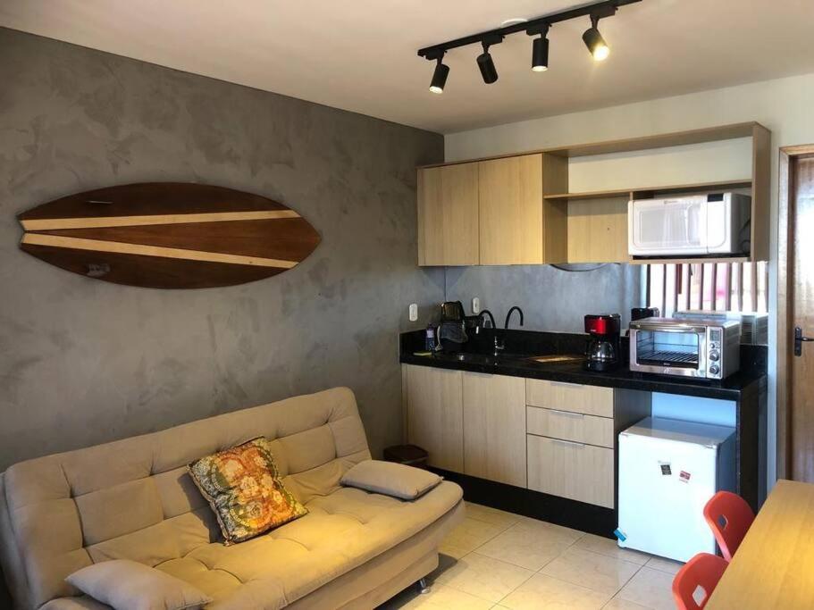 ein Wohnzimmer mit einem Sofa und einer Küche in der Unterkunft Excelente Loft 1 novíssimo no Centro de Saquarema in Saquarema