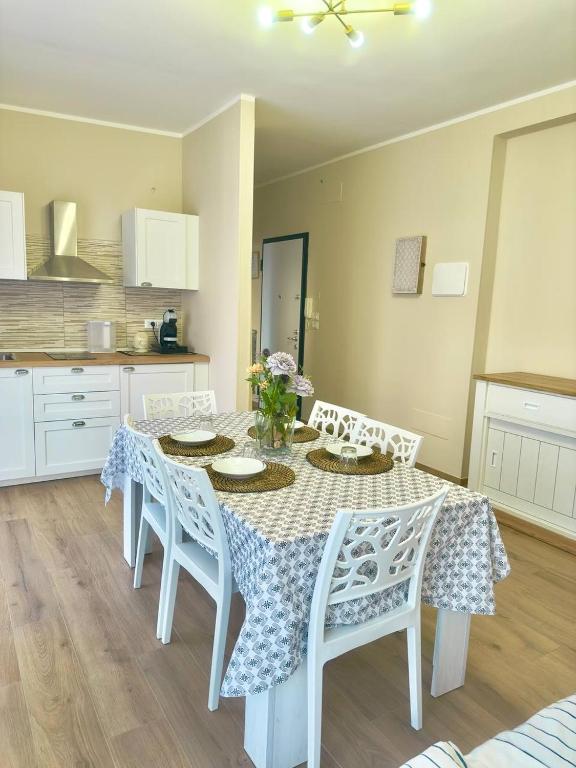 mesa de comedor con sillas blancas y cocina en Casa Luciana Apartment en San Giovanni Rotondo