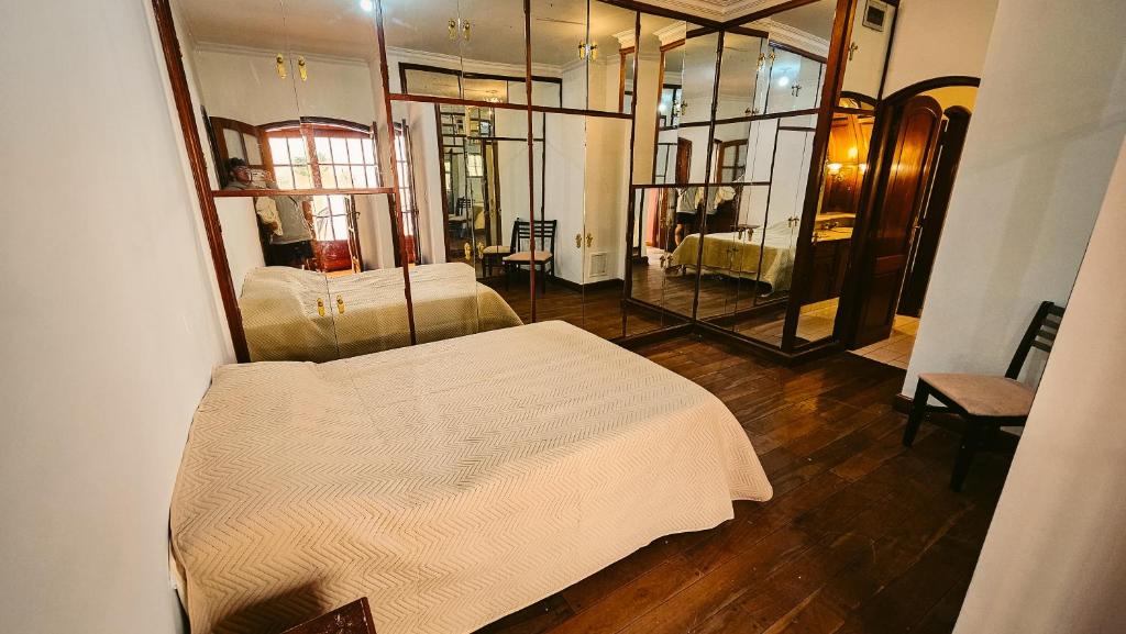 um quarto com uma cama branca e um espelho em Valhalla Hostel & Suites em Salta