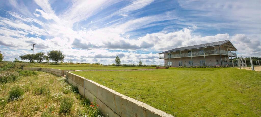 a large building with a grassy field in front of it at Nest Farmhouse in Docking