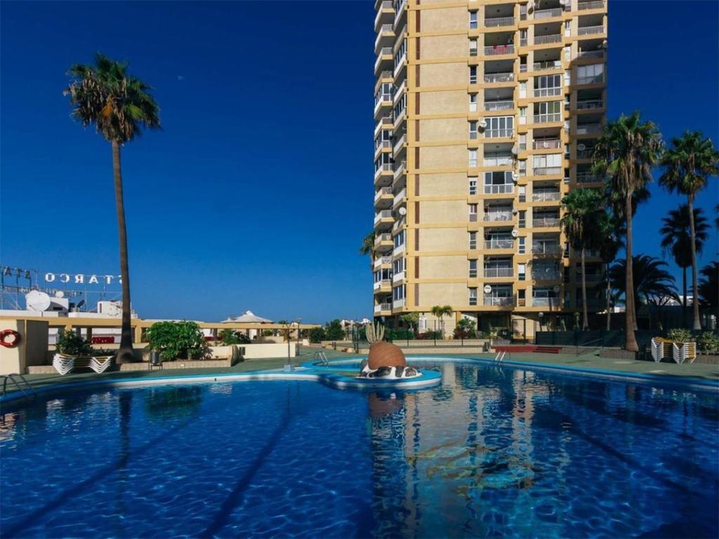 a swimming pool in front of a tall building at Full center of Las Americas, renovated, high floor in Playa de las Americas