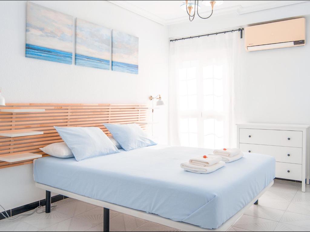 a white bedroom with a large bed with towels on it at Riverside Apartment in Triana in Seville