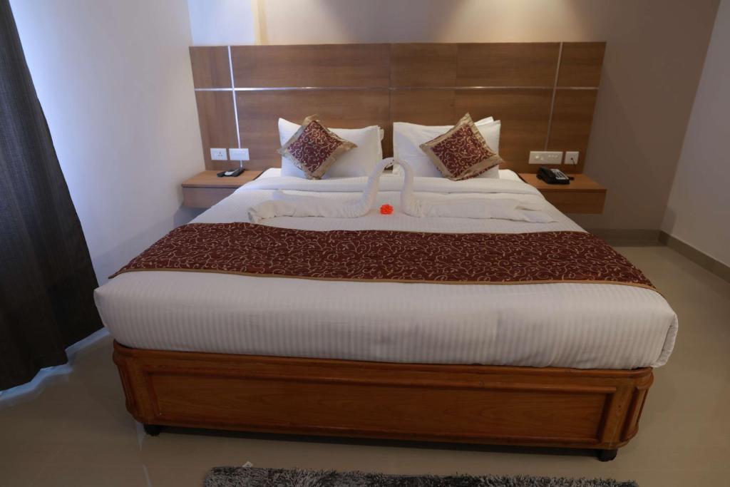 a bedroom with a large bed with a wooden headboard at Hotel Mangala Temple View in Guruvāyūr