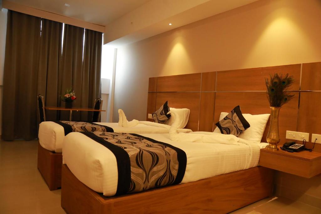 a hotel room with two beds in a room at Hotel Mangala Temple View in Guruvāyūr