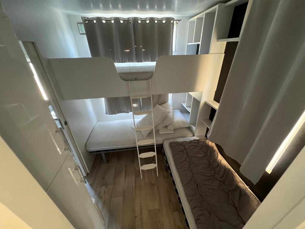 an overhead view of a tiny house with a bed and a ladder at Mobil Home confort 6p in Cadenet