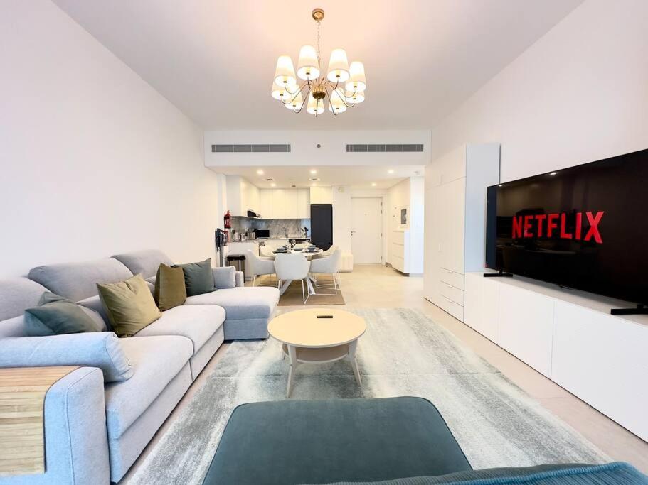 uma sala de estar com um sofá e uma televisão em Dar Vacation - Bright and Charming 1 BR Apartment em Dubai