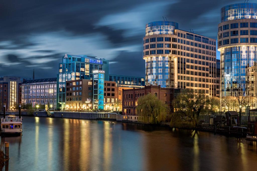 eine Stadt mit hohen Gebäuden und einem Fluss in der Nacht in der Unterkunft AMERON Hotel Abion Spreebogen Berlin in Berlin