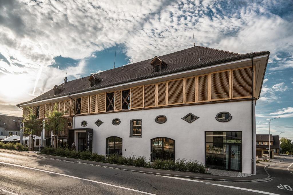 um edifício branco com persianas de madeira numa rua em Hotel Greuterhof em Islikon