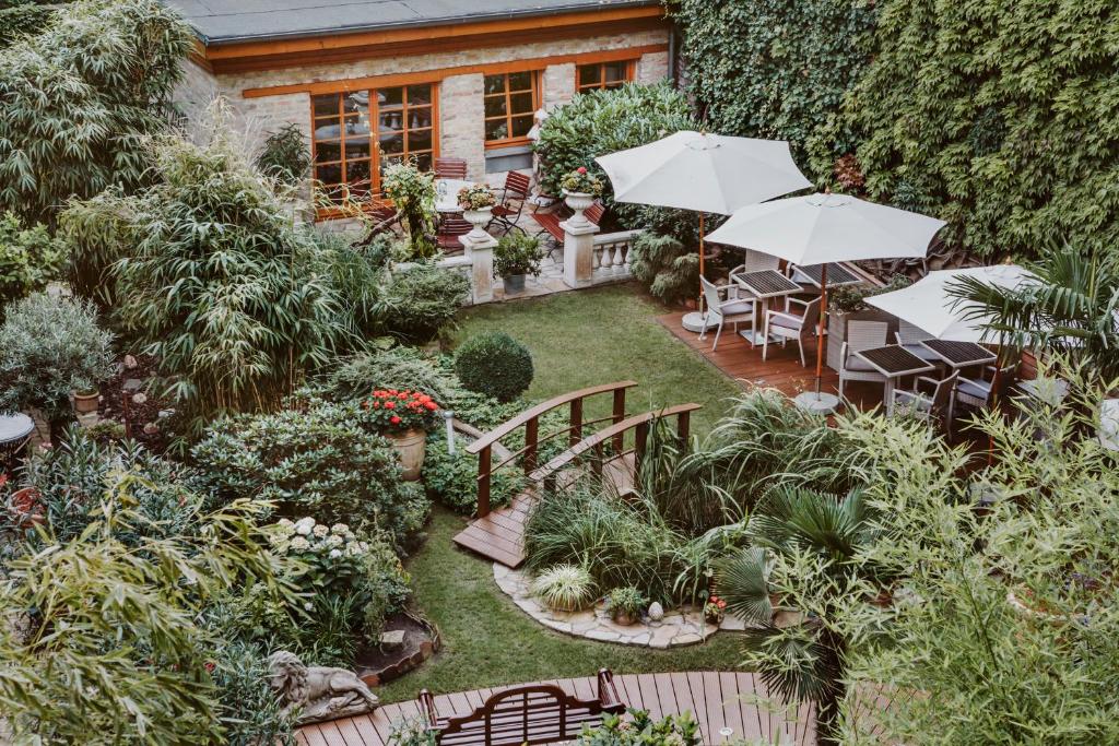 un jardín con mesas, sillas y sombrillas en Garden Boutique Hotel en Berlín