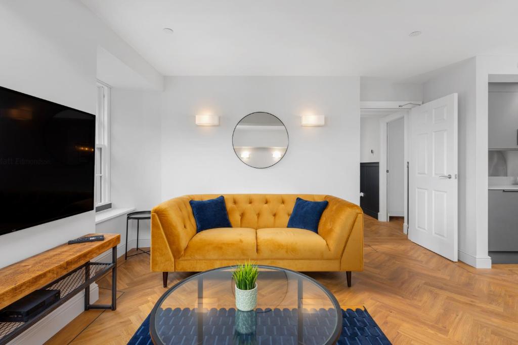 a living room with a yellow couch and a glass table at 314 Reids Corner - by StayDunfermline in Dunfermline