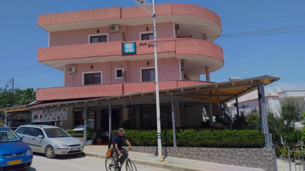 Un uomo che va in bicicletta davanti a un palazzo di Vila Spiro a Ksamil