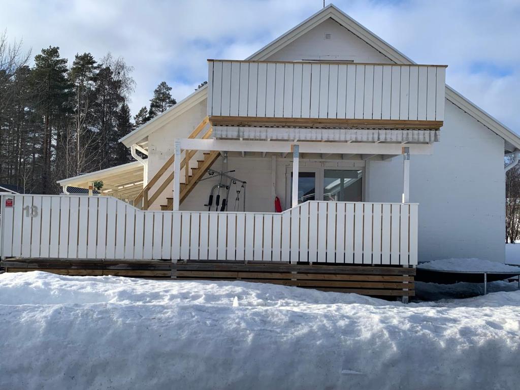 a house with a white fence in the snow at Fin Villa nära insjön Burtäsket in Burträsk