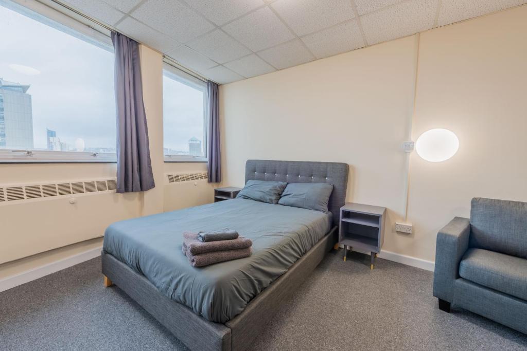 um quarto com uma cama, uma cadeira e uma janela em Superior En-suite Apartment 6 em Plymouth