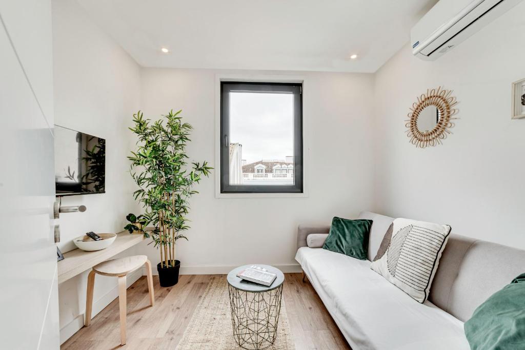 a living room with a white couch and a window at Lapa Stylish Apartments in Lisbon