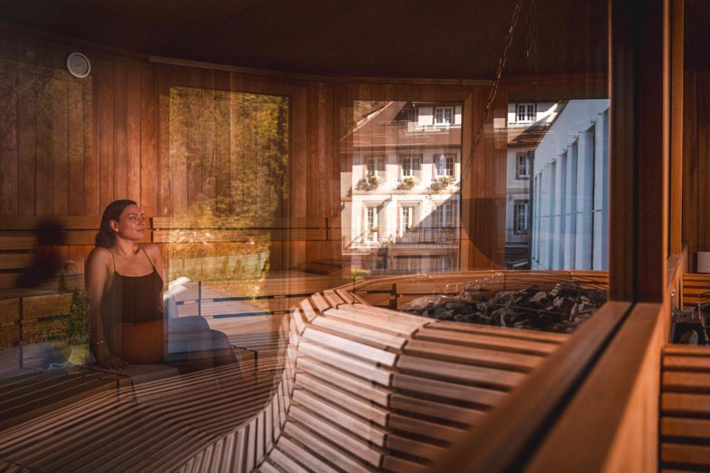 a woman standing in a room looking out a window at 6717 Nature Hôtel &amp; Spa Le Clos des Délices in Ottrott