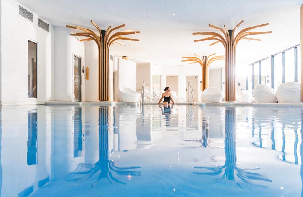 a woman sitting in the water in a swimming pool at 6717 Nature Hôtel &amp; Spa Le Clos des Délices in Ottrott