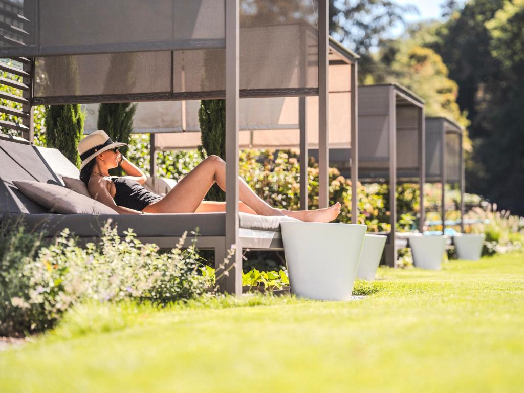 a woman sitting on a bench talking on a cell phone at 6717 Nature Hôtel &amp; Spa Le Clos des Délices in Ottrott
