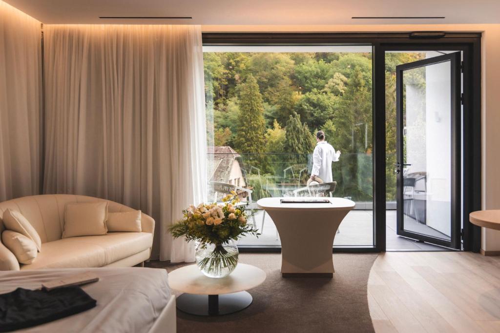 a living room with a couch and a room with a balcony at 6717 Nature Hôtel &amp; Spa Le Clos des Délices in Ottrott