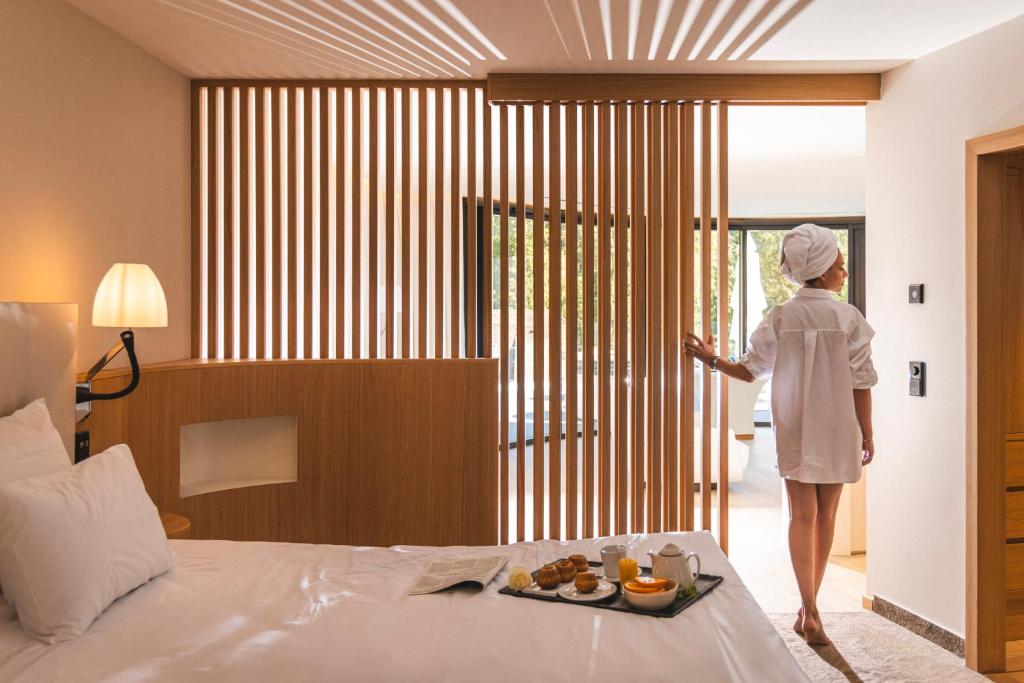 a woman is looking out the window of a hotel room at 6717 Nature Hôtel &amp; Spa Le Clos des Délices in Ottrott