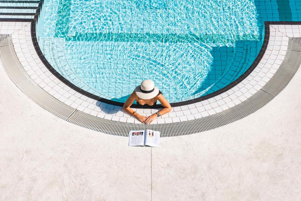 a man in a hat sitting in a swimming pool at 6717 Nature Hôtel &amp; Spa Le Clos des Délices in Ottrott