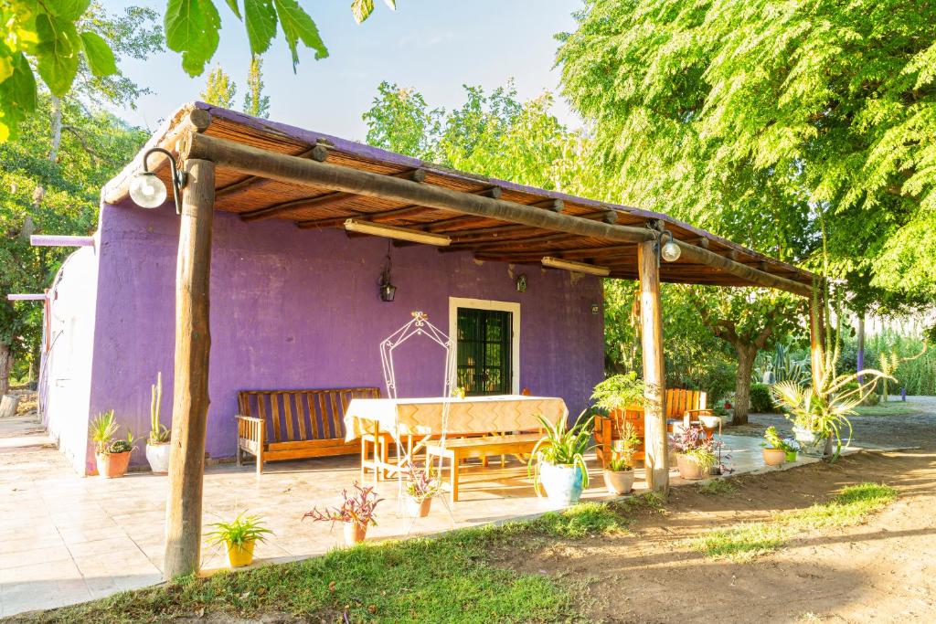 une terrasse avec une maison violette dotée d'une table et de chaises. dans l'établissement Casa de Campo La Lila, à Pocito