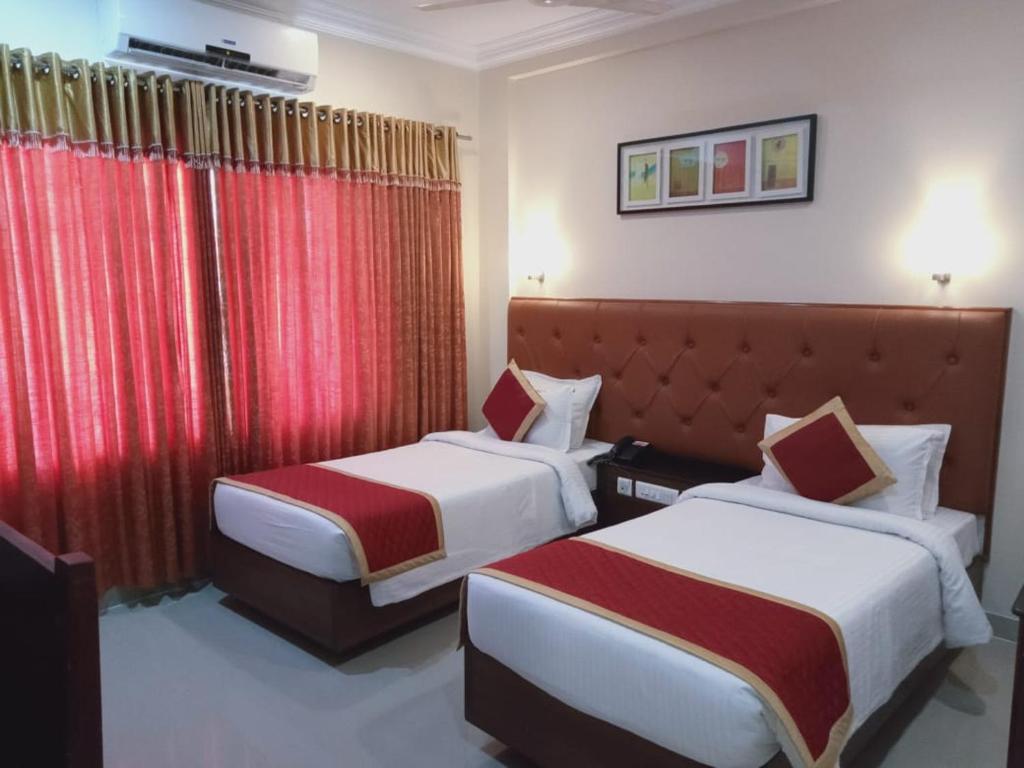 two beds in a hotel room with red curtains at HOTEL SAHANA CASTLE in Nāgercoil